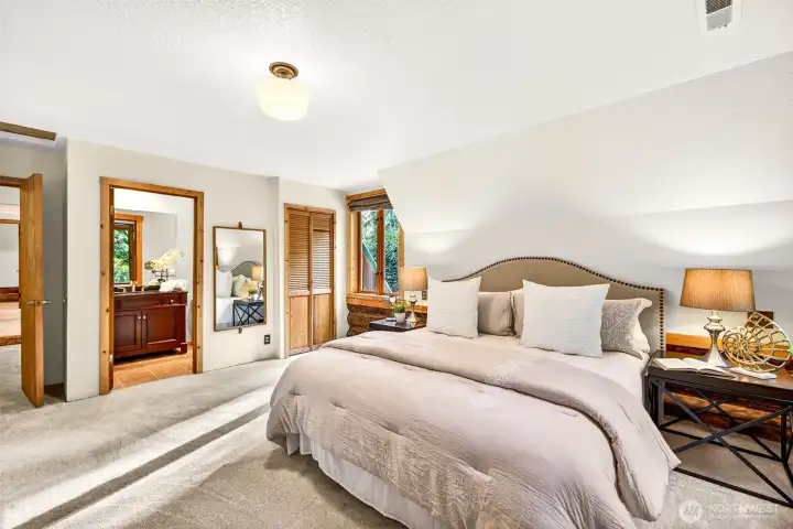 The primary suite offers a thoughtful and serene escape — with a private ensuite bath, louvered closet doors, and soft natural light from forest-facing windows, this is a bedroom designed for rest, privacy, and everyday comfort.