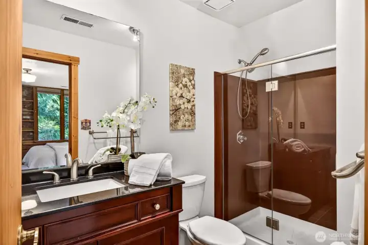The updated primary ensuite bath delivers a polished, private retreat — a rich mahogany vanity with granite countertop, undermount sink, and a glass-enclosed shower offer a clean, refined finish that complements the warmth and character of this exceptional home.
