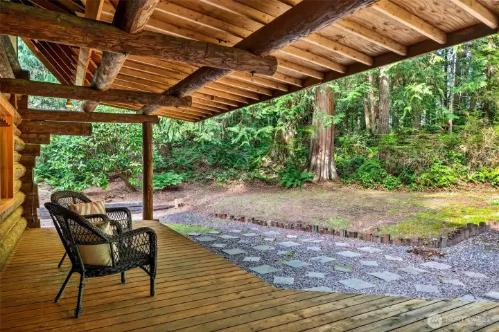 The covered lower deck, framed by hand-hewn log beams and open to a sweeping view of the forested grounds, offers a sheltered outdoor retreat that works in every season — a truly private sanctuary on nearly 4 acres of Woodinville woodland.