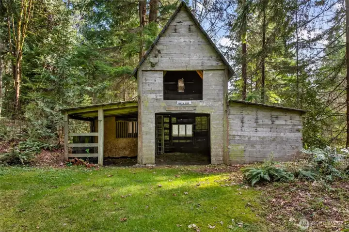 A secondary outbuilding tucked into the forest edge adds rare flexibility to an already exceptional acreage property — with a covered stall bay and open interior, it presents compelling potential for storage, workshop, or hobby use, subject to buyer due diligence.
