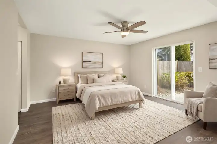 The larger primary bedroom suite with ceiling fan, luxury vinyl plank flooring, new slider doors leading out the the back patio, fresh paint, dual walk-in closets, and a brand new bathroom to enjoy!    Virtually staged.
