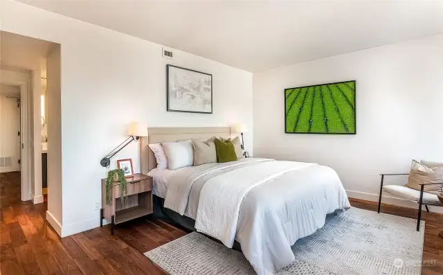 The primary bedroom is generously spacious, with walnut flooring extending throughout the entire unit