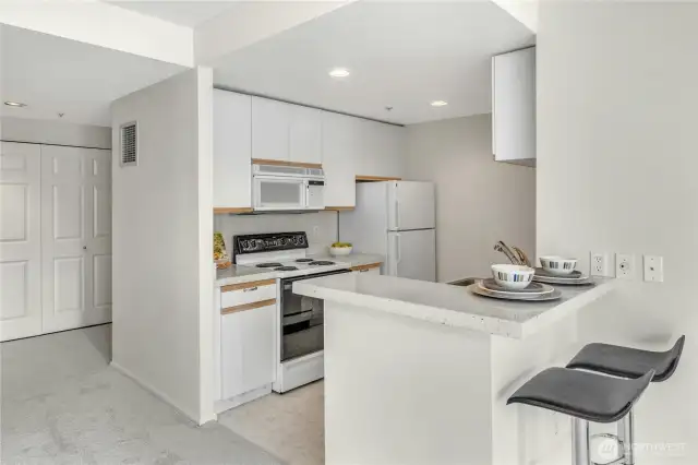 The kitchen features bar seating. Laundry closet in the background.