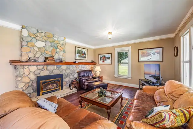 Step into comfort! The cozy living room features a stunning river rock fireplace with insert, creating the perfect gathering space. Large windows frame breathtaking views in every direction—bringing the beauty of the outdoors in.