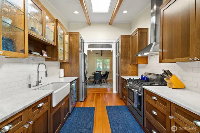 Well-functioning galley style kitchen is a true show piece with solid wood cabinetry, high end appliances, and a large farm sink with gooseneck faucet.