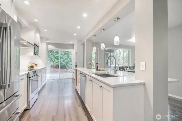Modern permitted updated open concept kitchen with pull outs, bar seating, stainless appliances, stone countertops, brushed nickel hardware, pendant lights, can lights, undermount lighting.
