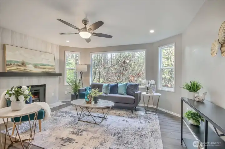 living room with big picture window vinyl plank floors, fireplace with modern finishes.