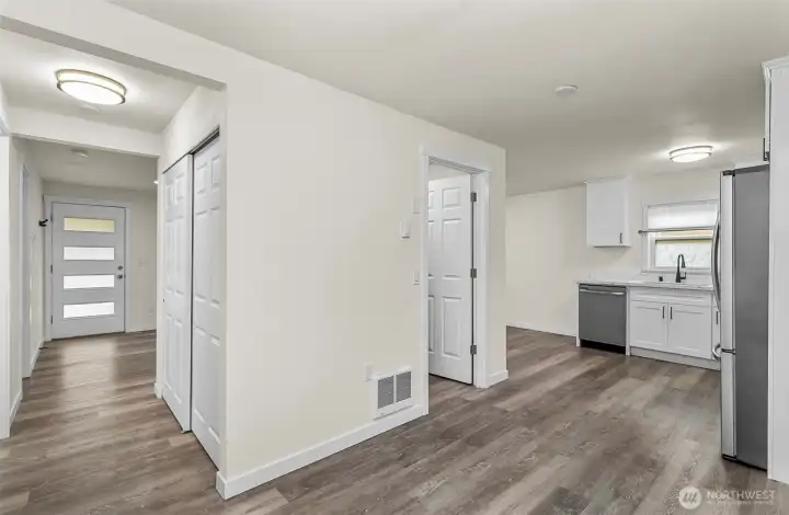 View from the dining area showing the flow, linen closet, laundry room, kitchen, front hallway