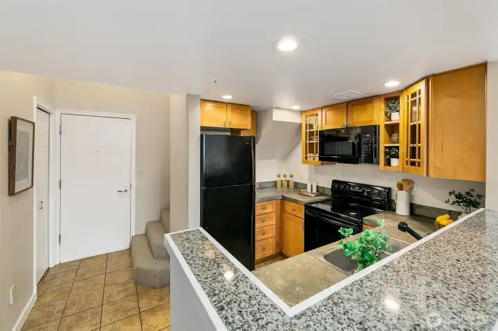 Open kitchen with tile floors, concrete counters, and great cabinet space. In-unit W/D in the closet on the left.