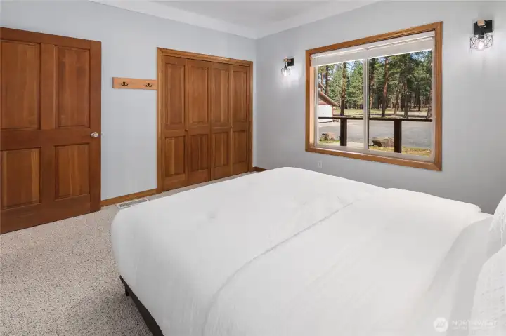 A bright and welcoming main-level guest bedroom with expansive windows showcasing the grounds.