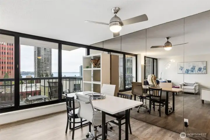 Dining room offers a wall of mirrors + floor to ceiling windows with a ceiling fan.