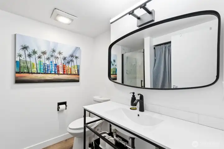 Remodeled bathroom featuring an industrial-style vanity, new luxury vinyl plank flooring, and walk-in shower.