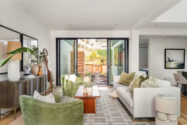 The spacious living room provides access to both the front patio and back garden through large sliding glass doors, creating a seamless indoor-outdoor flow that enhances the sense of space and natural light.