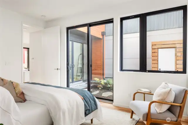 The main floor primary bedroom offers direct access to the private garden space through a large sliding glass door, creating a seamless connection between indoor comfort and outdoor tranquility.