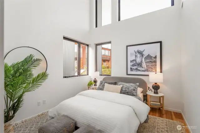 The second primary bedroom features soaring ceilings, large windows, and direct access to the full bath upstairs, creating a spacious and inviting retreat.