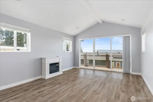 Primary bedroom w/ electric fireplace and deck access.