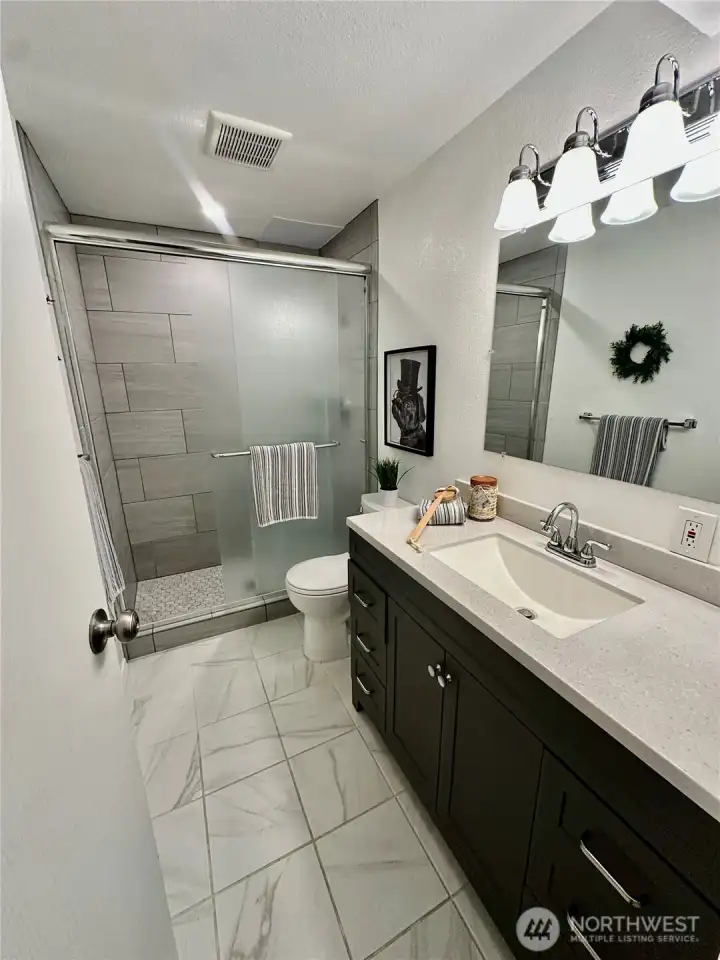 Updated lower bath with tile floors and stylish shower. Newer vanity with solid surface counters.