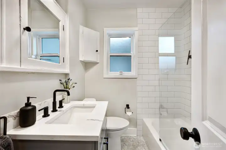 Remodeled main floor full bathroom with tile floor and tub surround.