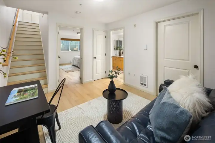 All right, we've made it downstairs, at the top of the stairs you can see the front door. This is a great flex space for office, guests, etc. Primary bedroom is through the open door, and then off to the right you can see cabinets within your full en suite bath. Door to the right is a utility closet with a full size washer and dryer.