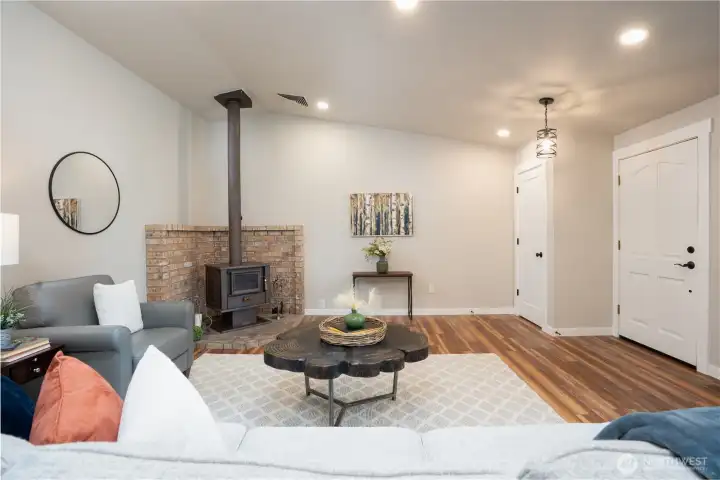 View of interior front entry, coat closet and wood stove with brick surround.