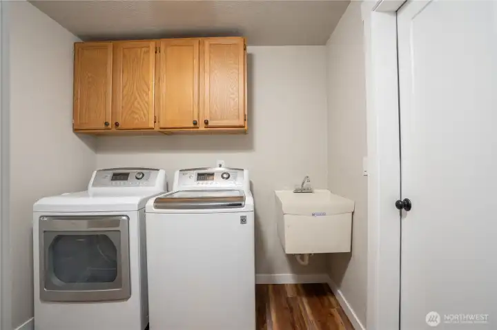 Utility room features cabinets for storage & sink, door to the right leads to garage. Washer & Dryer convey