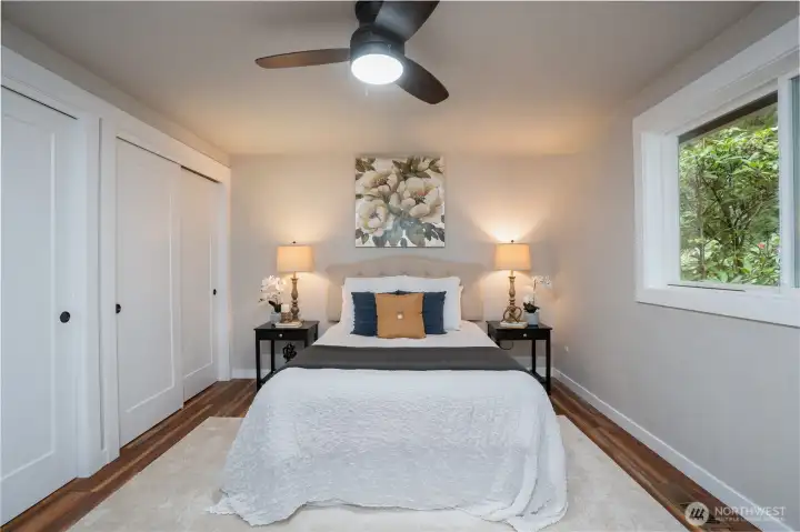 Another view of the primary en suite with two closets, new mill work, doors and adjoining updated 3/4 bathroom