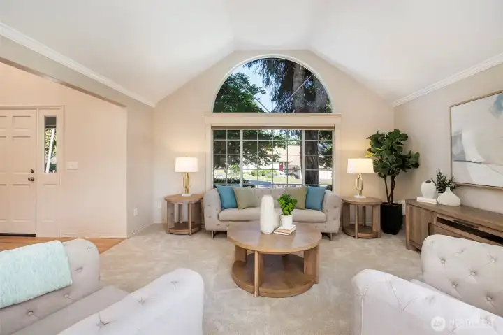 Living room features crown moldings, vaulted ceiling & sunburst front window