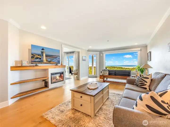 Open concept living area filled with natural light, ocean views, and a cozy fireplace.