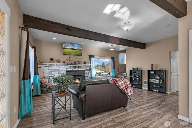 Front entry and living room with woodstove insert and exposed wood beams, lots of natural lighting