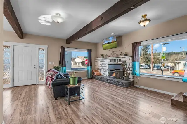 Front entry and living room with woodstove insert and exposed wood beams, lots of natural lighting