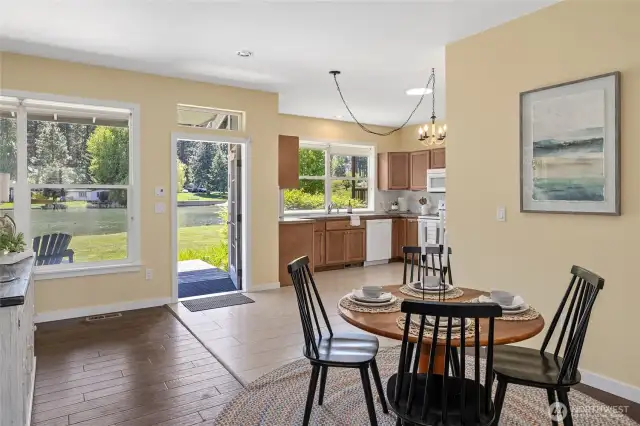 Bright dining and kitchen area with scenic water views, natural light, warm wood cabinetry, and seamless indoor-outdoor flow.