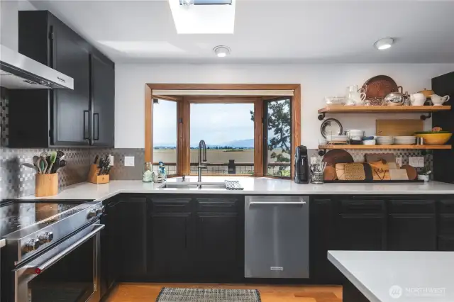 Super convenient kitchen with ample counter space, stainless appliances, open shelving, skylights for added light, island with built in microwave and wine frig. Quartz counters, stainless backsplash and picture window showcasing the gorgeous views!
