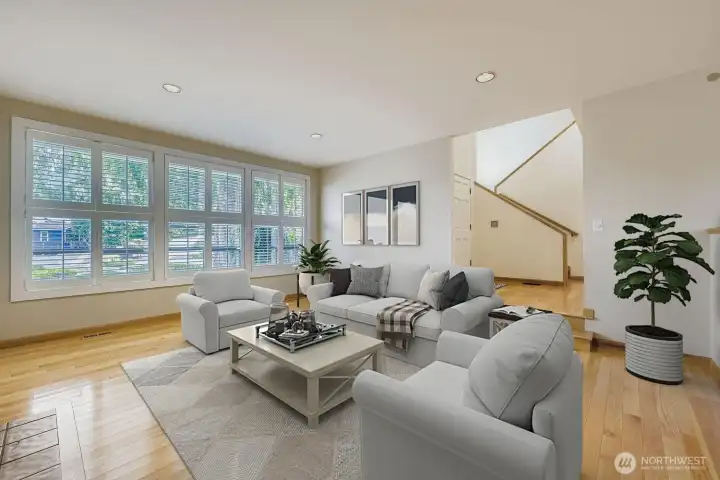Step down into the living room with its gleaming hardwood floors, wall-to-wall windows to the front and beautiful plantation shutters.