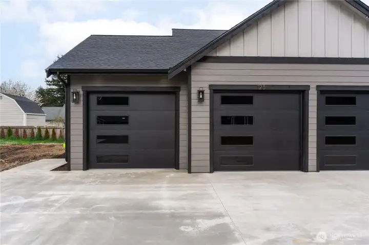 Three-car garage with sleek black-trimmed glass panel doors