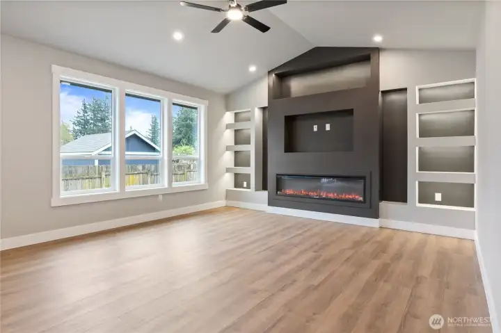 Living room with electric fireplace, built-in shelving, and LVP flooring
