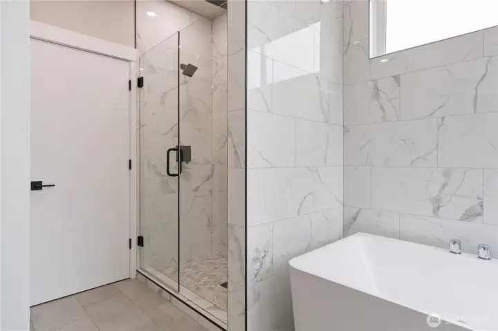 Primary bath frameless glass shower with marble tile surround