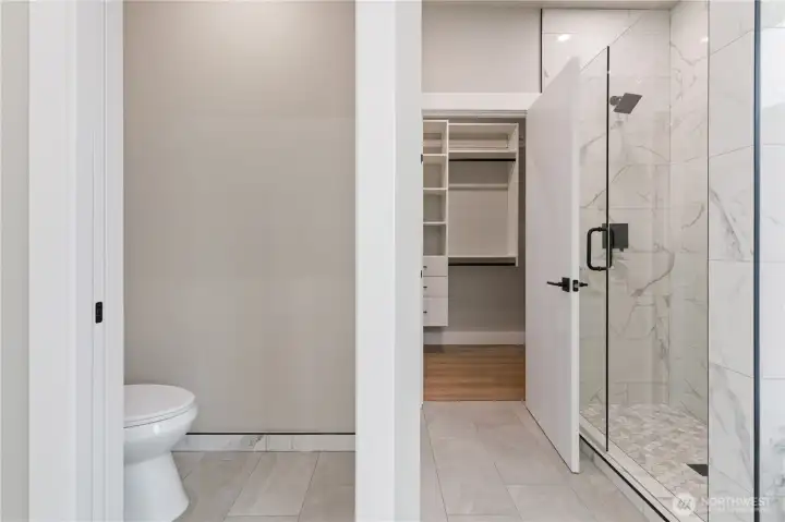Primary suite entrance with walk-through to custom closet and marble bath