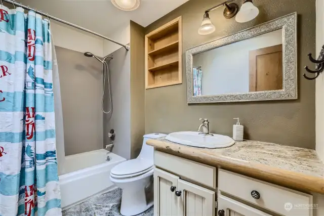 Upstairs main full bathroom features slate flooring, white cabinets and a skylight.