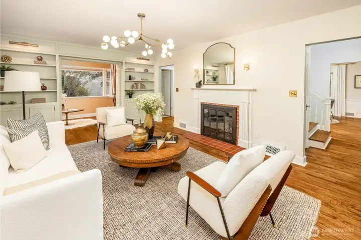 Wood burning fireplace with flanking scone lighting, recessed bookshelves with lighting and cabinet storage.