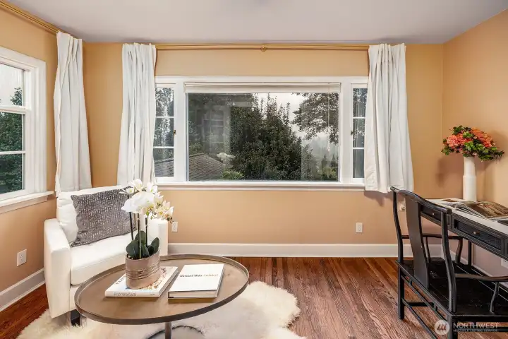 A light-filled office or study, framed by glass-paneled doors for privacy, overlooks the lush backyard and flows gracefully from the elegant living room.