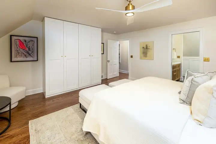 Another view of the primary suite looking toward the closet, circulating ceiling fan and spa bathroom.