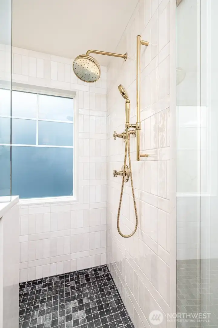 Fully tiled large walk in shower with Kohler rain shower head, shower wand, shower mount, faucets.