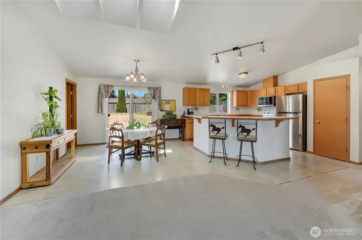 From the great room looking into the dining area and kitchen. The door on the right is the pantry. The sliding door leads to the mostly flat, spacious back yard. Vinyl flooring makes for easy maintenance all around.