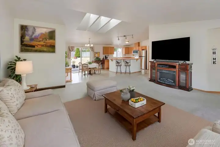 Love this bright and spacious great room that's open to the dining and kitchen areas! The furnishings in the lower part of the photo are virtually staged, but the Electric fireplace TV console is real and stays with the house, but the TV does not.