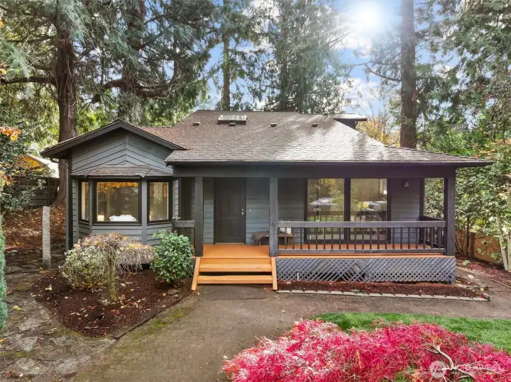 Cozy, covered front porch offering privacy and tranquility in a wooded setting with lovely landscaping.