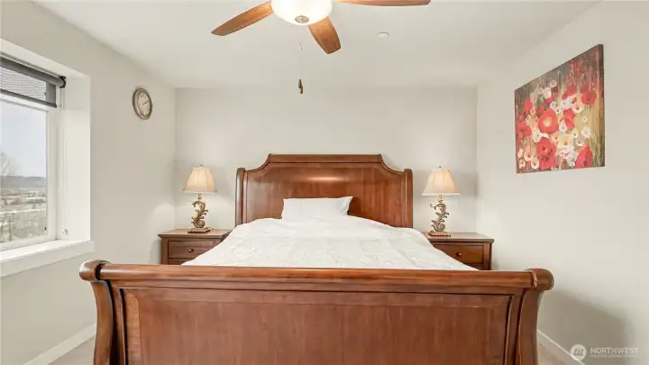 Primary suite features a ceiling fan and a large window that fills the room with natural light