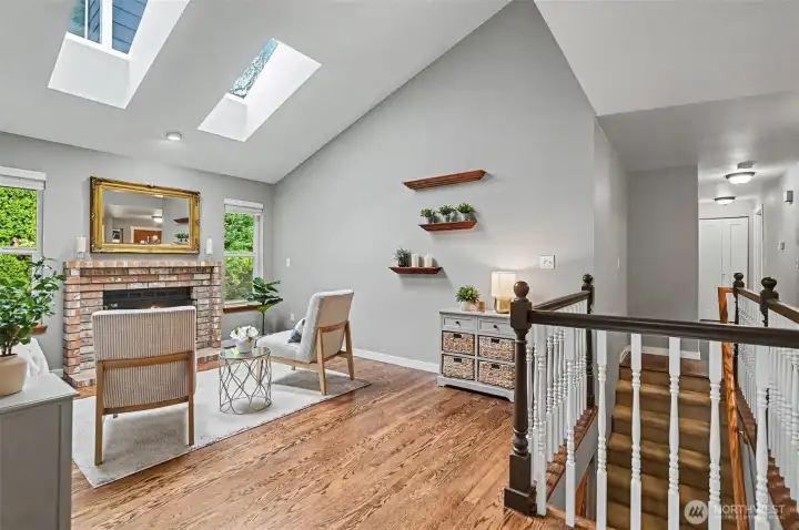 Formal living room is warm and inviting featuring vaulted ceilings, skylights and a gas fireplace.