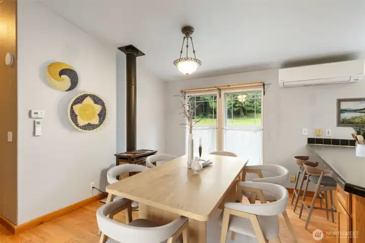 Sitting area near the bar counter, adjacent to the kitchen, a propane woodstove can supplement the heat provided by the mini-split HVAC seeing on the wall. This area WAS used as a sitting area with a nice rocking chair- it's been virtually staged as a dining space. The choice is up to you!