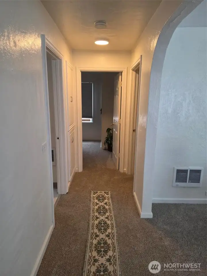 Looking down hallway, from kitchen to primary bedroom, at end and 2nd bedroom at door to right. Bathroom at first door on the left.