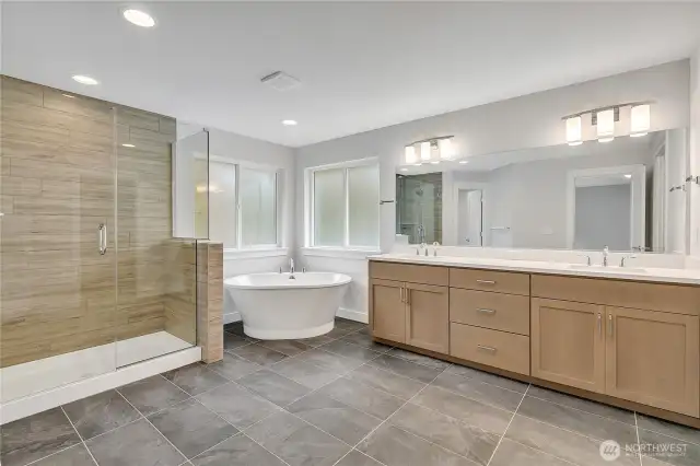 Spa inspired primary bathroom with a dual sink vanity, soaking tub, and spacious shower.
